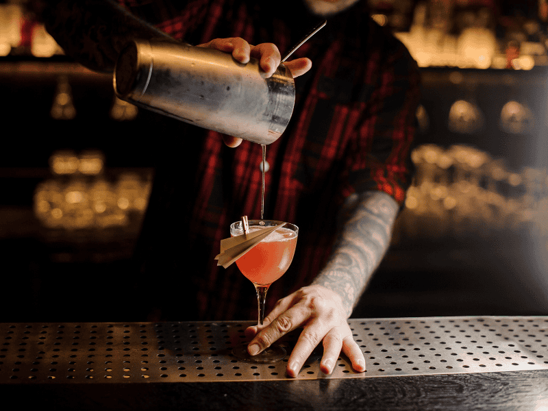 Brindis con cóctel en bar con ambiente cálido y acogedor.